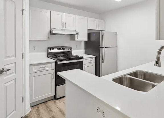 A modern kitchen with white cabinets and stainless steel appliances.