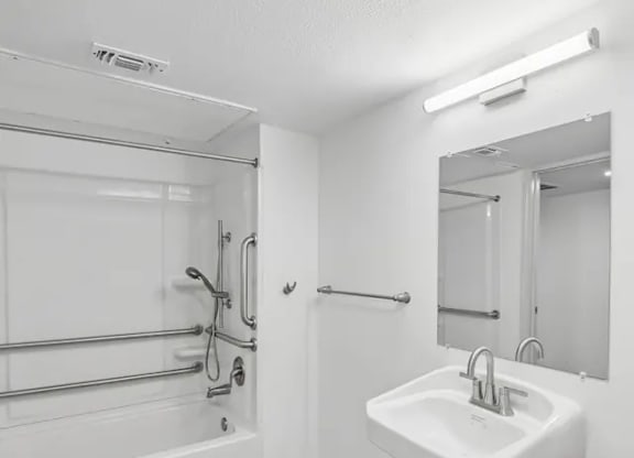 A white sink is mounted on a wall next to a glass shower stall.