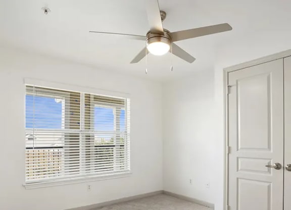 A room with a ceiling fan and a door.