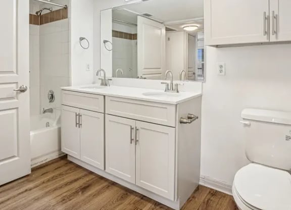 A white bathroom with a toilet, sink, and mirror.