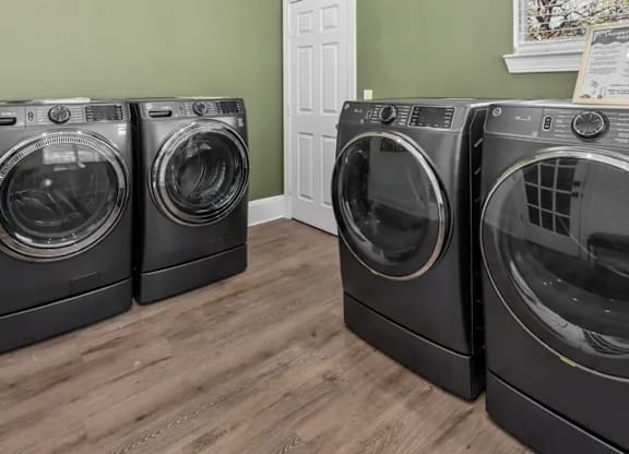 Three front load washing machines in a laundry room.