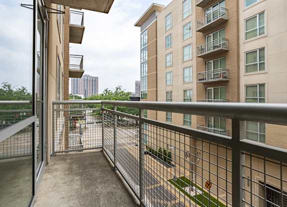A balcony with a metal railing and a view of a cityscape.