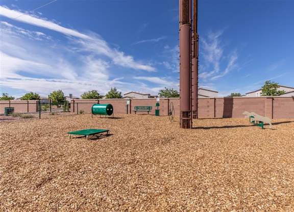 A playground with a green slide and a brown pole.