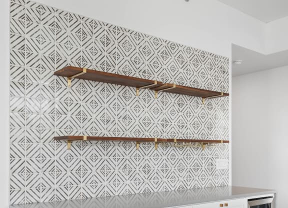 a living room with white cabinets and a wall with a white and white geometric wallpaper