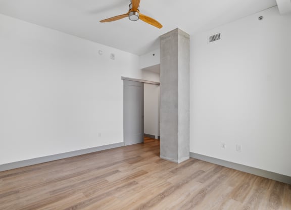 a living room with white walls and wood floors and a ceiling fan