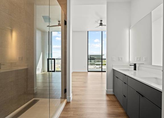 A modern bathroom with a walk-in shower and a view of the ocean.