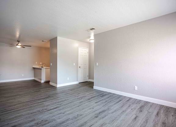 an empty living room with wood floors and a ceiling fan