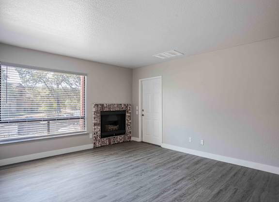 an empty living room with a fireplace and a window