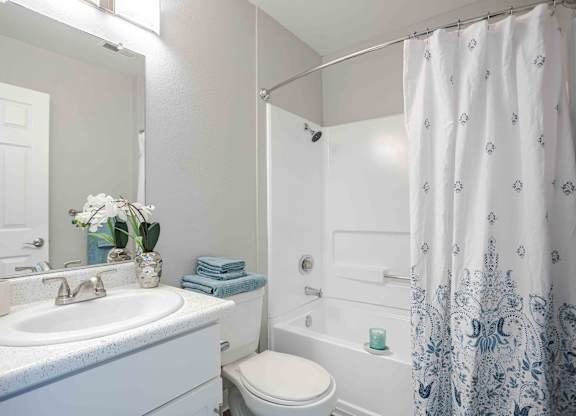 a white bathroom with a shower and a sink and a toilet