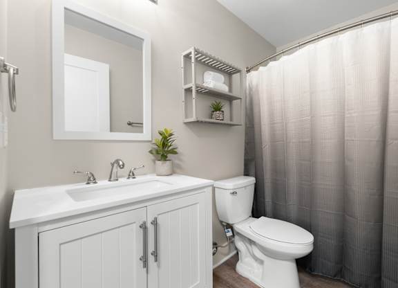 A white bathroom with a toilet, sink, and shower curtain.