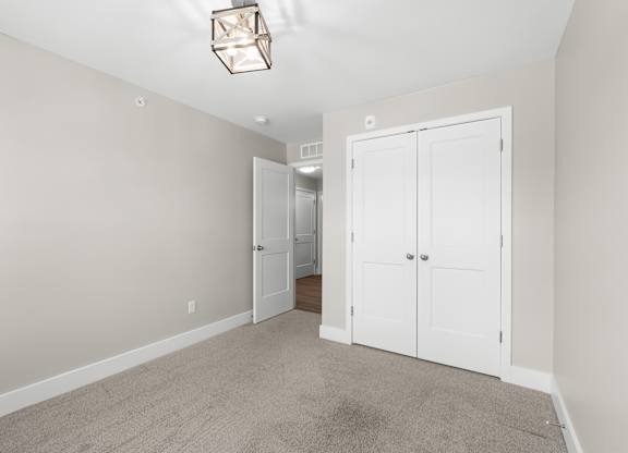 A room with a white door and a carpeted floor.
