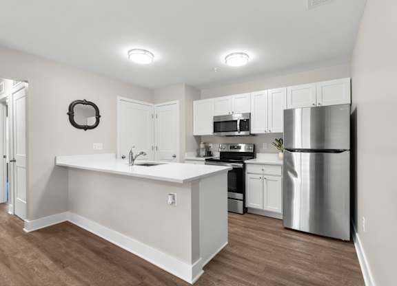 A kitchen with white cabinets and a stainless steel refrigerator.