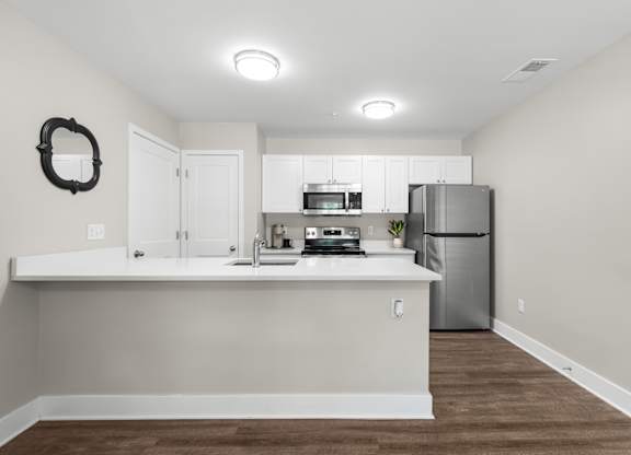 A kitchen with white cabinets and a fridge.