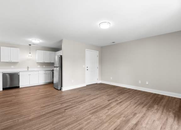 A kitchen with white cabinets and a wooden floor.