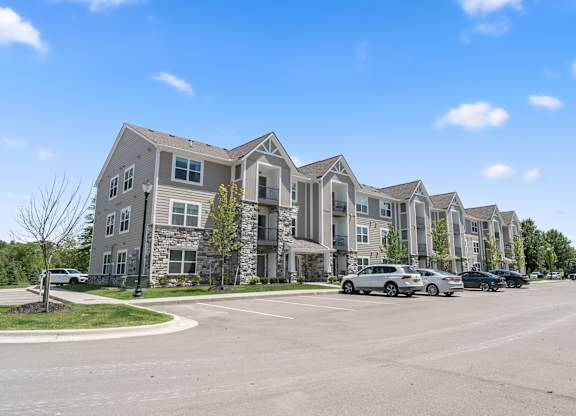 A row of modern townhouses with cars parked in front.