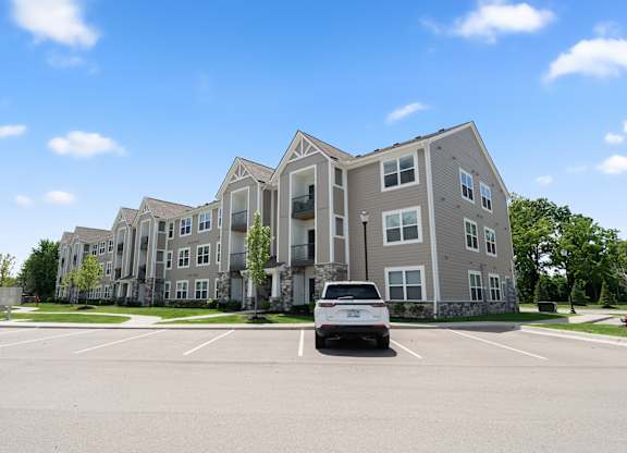 A white van is parked in a parking lot in front of a large apartment building.