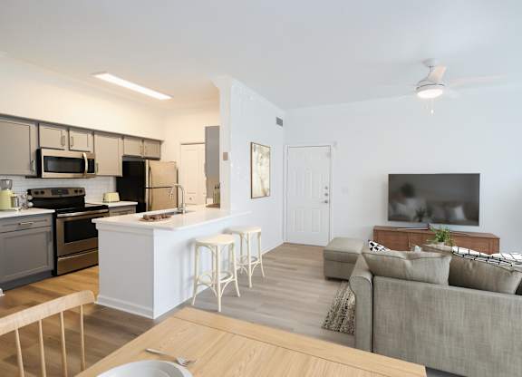 A modern kitchen with a breakfast bar and a grey couch.