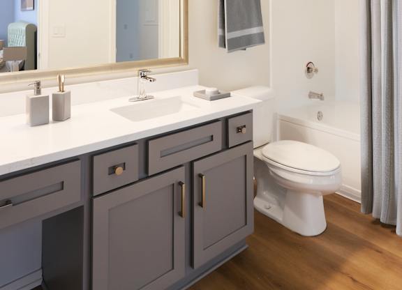 A bathroom with a white counter top and a white toilet.