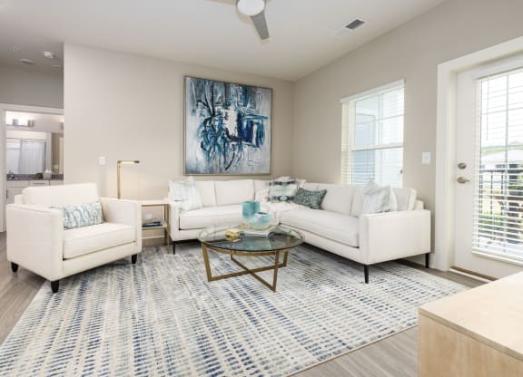 a living room with white couches and chairs and a rug