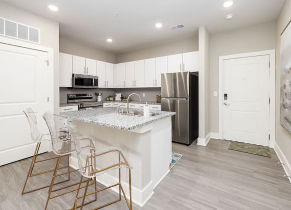 a kitchen with white cabinets and a marble counter top and a stainless steel refrigerator