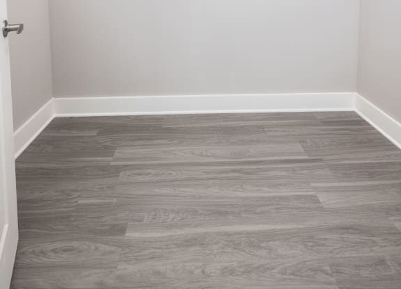 an empty closet with white walls and wood flooring