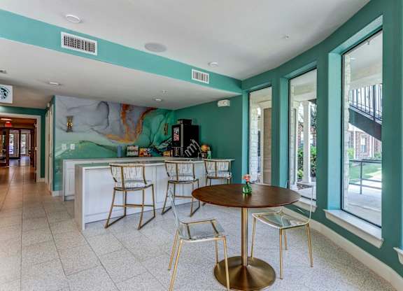 a room with a table and chairs in front of a window with a mural on the wall