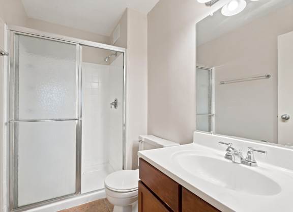 A white bathroom with a toilet, sink, and shower.