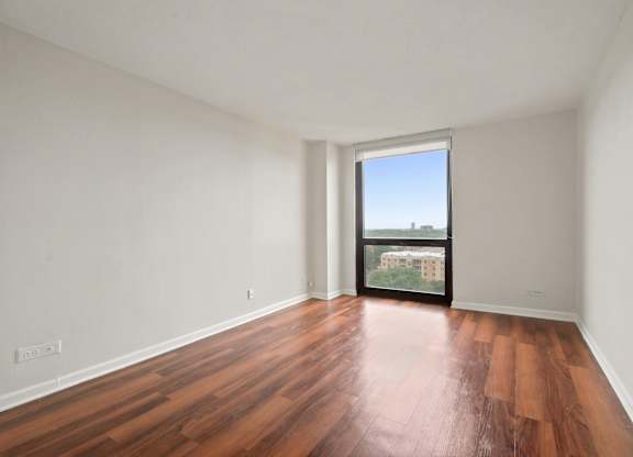 A bedroom with wooden floors and floor to ceiling windows.