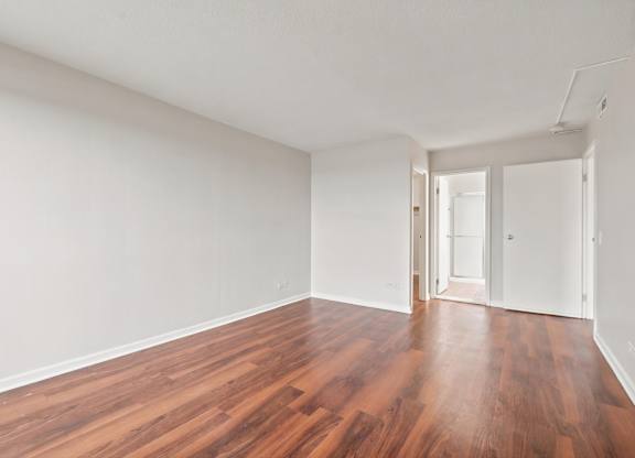 A bedroom with wooden floors and white walls.