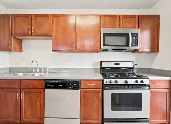 A tiled kitchen with a stainless steel stove, oven, dishwasher, sink, and microwave.