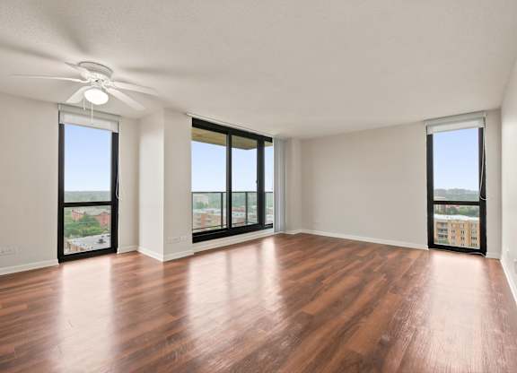 A living room with wooden floors, ceiling fan, and floor to ceiling windows.