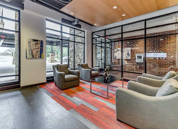 A waiting area with grey chairs and a red carpet.
