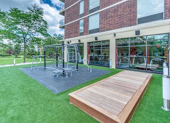 A playground with a wooden platform and a climbing frame is situated in a grassy area.