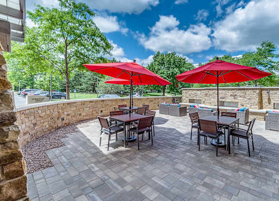 A patio with a table and chairs under red umbrellas.