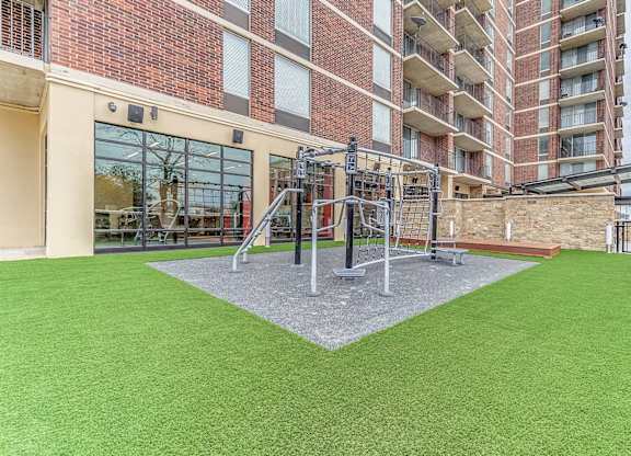 A playground with a slide and a green surface.