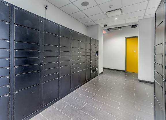 A hallway with a yellow door and black lockers on both sides.