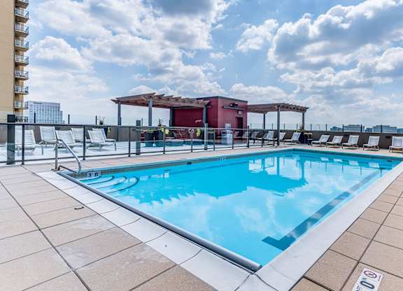 A large outdoor swimming pool with a red building in the background.