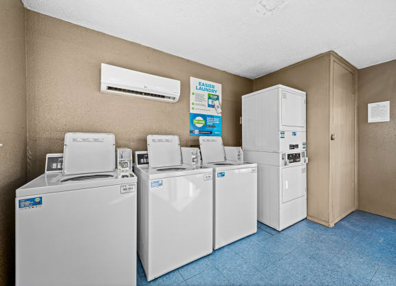 four sets of washing machines and refrigerators in a utility room with a row of
