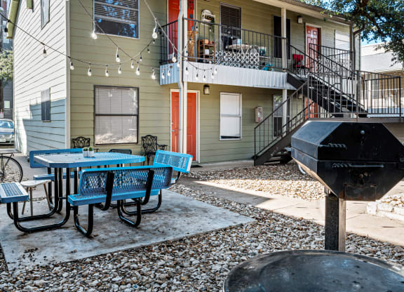 a patio with a table and chairs and a grill in front of a house