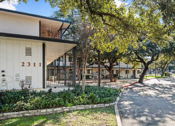 a building with a yard and trees in front of it