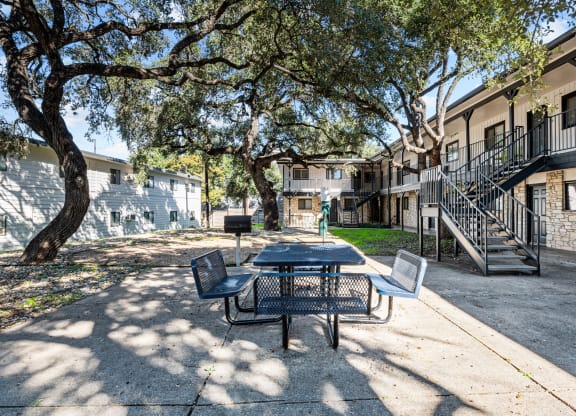 our apartments have a patio with a table and chairs and trees