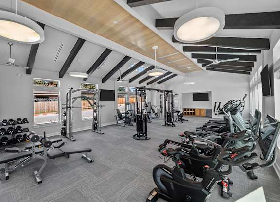 A gym with a variety of equipment including treadmills, weights, and exercise machines.