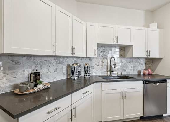 A kitchen with white cabinets and a marble backsplash.at Fora Apartments, Las Vegas, NV 89183
