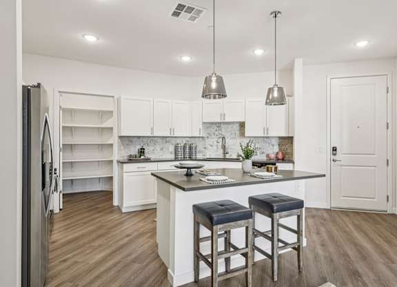 A kitchen with white cabinets and a marble island.at Fora Apartments, Nevada