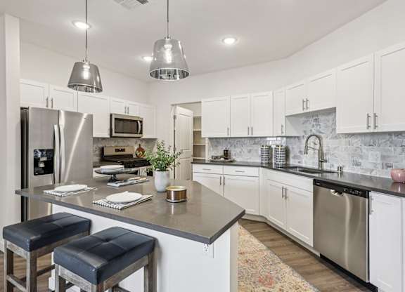 A kitchen with a bar area and stools.at Fora Apartments, Las Vegas