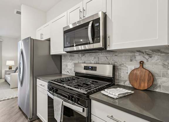 A modern kitchen with a stainless steel refrigerator, microwave, and oven.at Fora Apartments, Las Vegas, NV