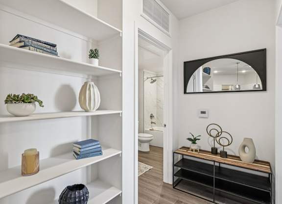 A bathroom with a mirror and a shelf with decorative items.at Fora Apartments, Las Vegas
