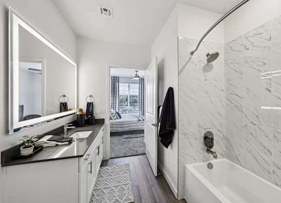 A bathroom with a marble wall and a white bathtub.at Fora Apartments, Nevada, 89183