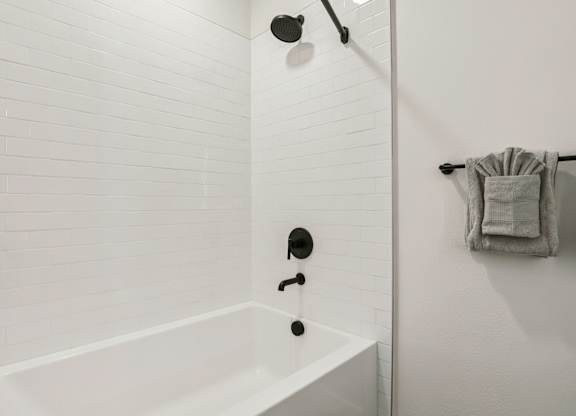 A white bathroom with a white tub and white tiles. at Lura Vegas Apartments, Las Vegas, NV