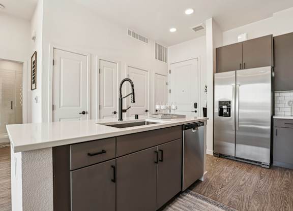A modern kitchen with a white countertop and dark brown cabinets. at Lura Vegas Apartments, Las Vegas, Nevada